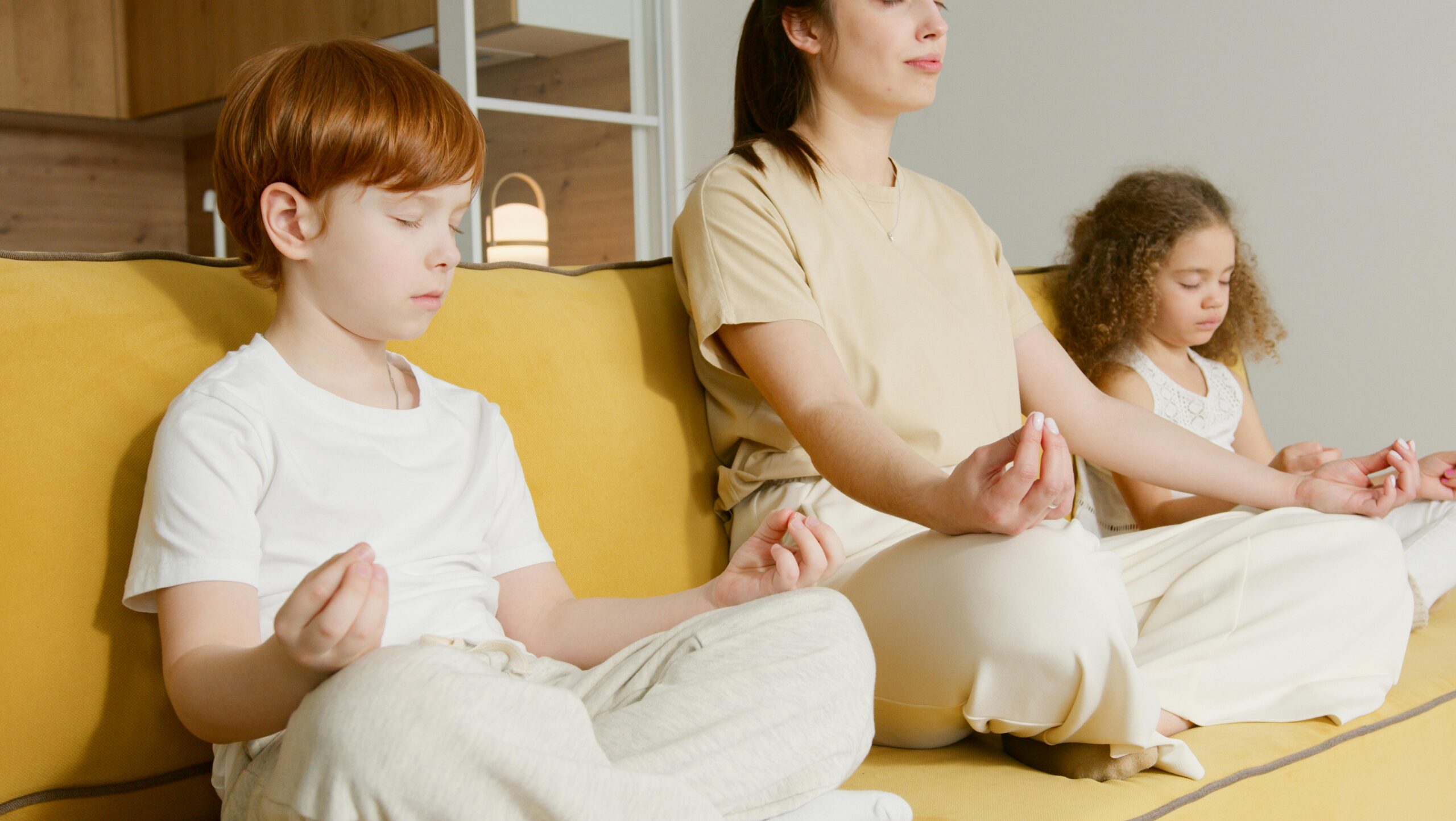 Image of mother and two kids doing meditation with one another.
