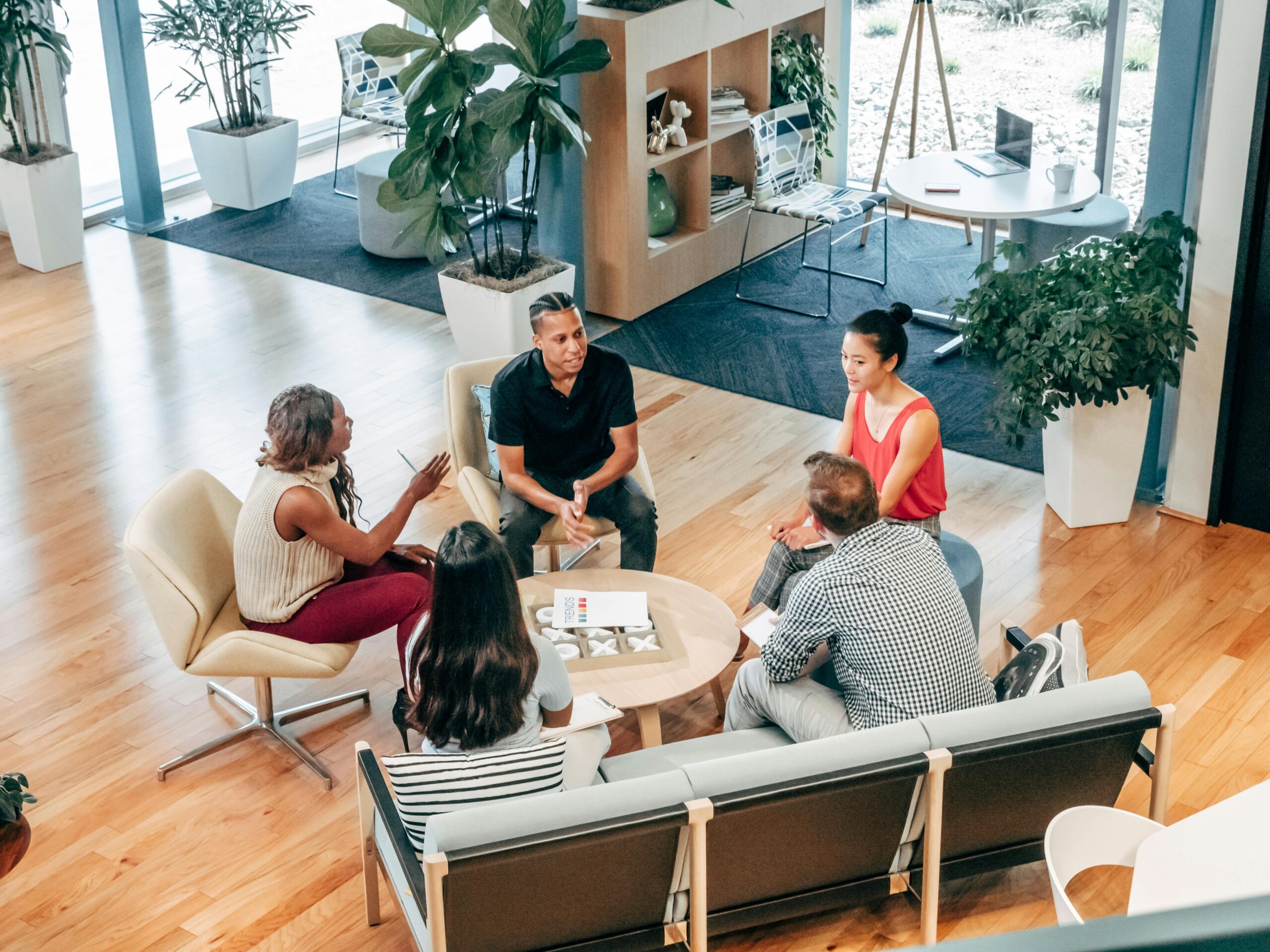 Image of five people sitting in circle and conversing with one another.