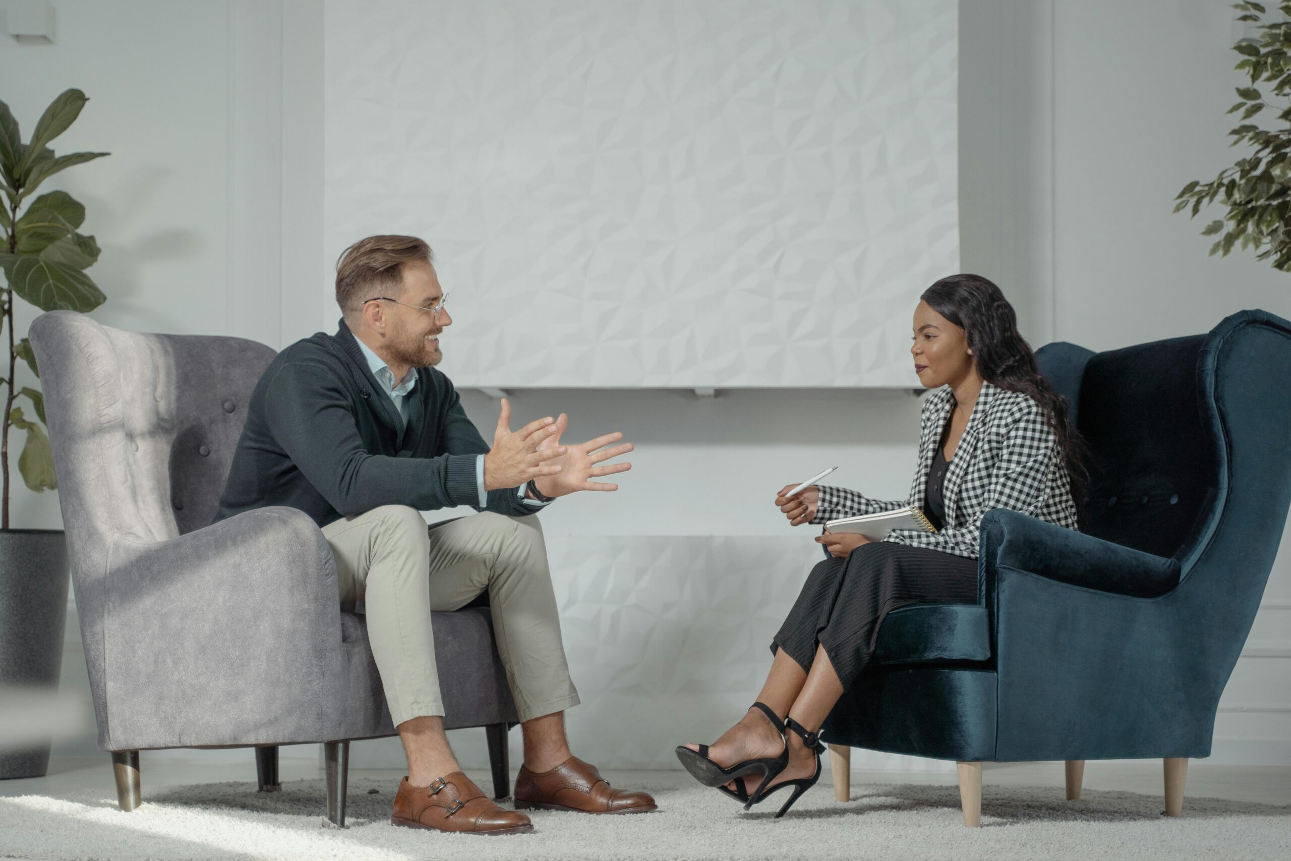Image of male patient and female therapist speaking to one another in office.