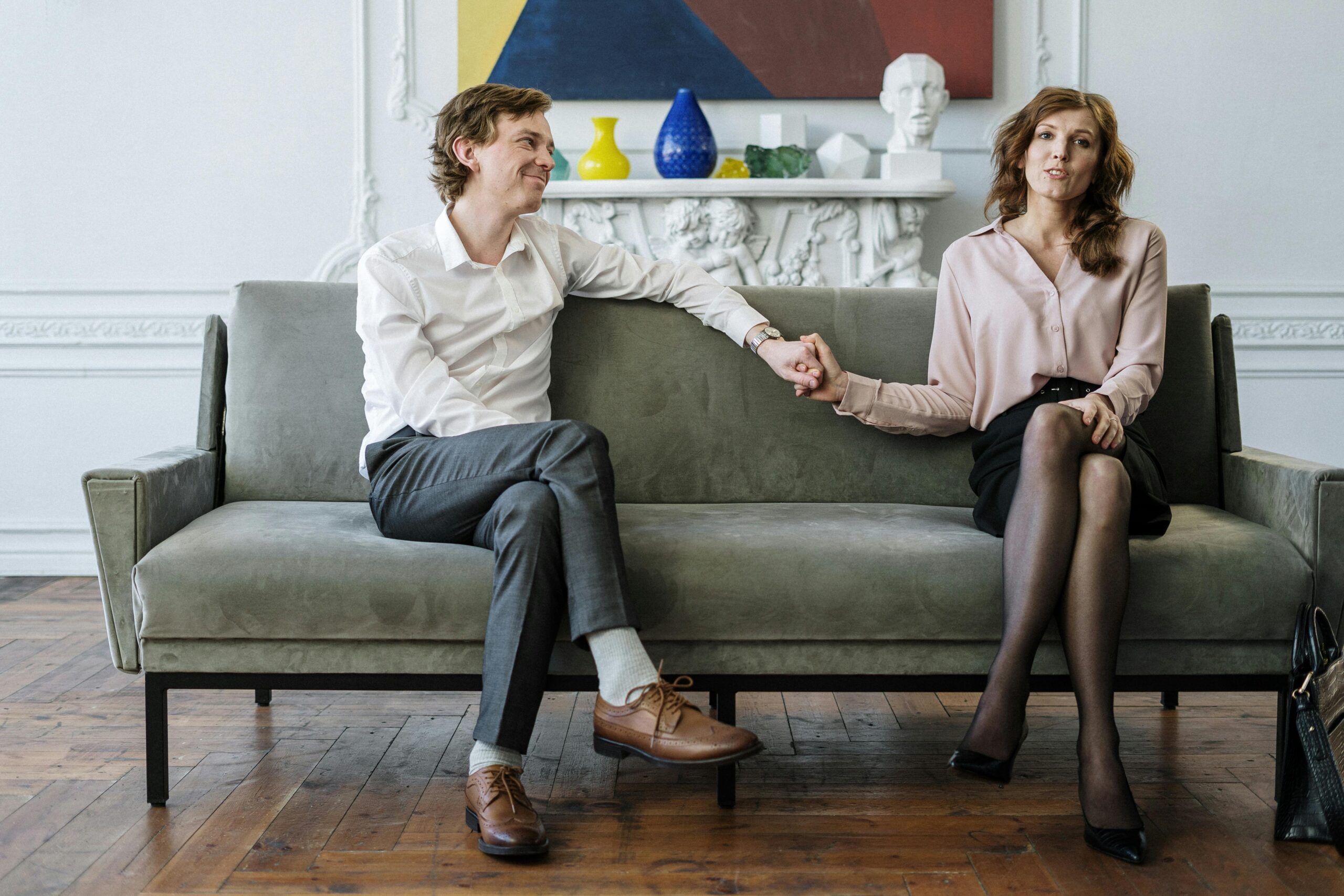 Image of couple holding hands on couch in therapist office.