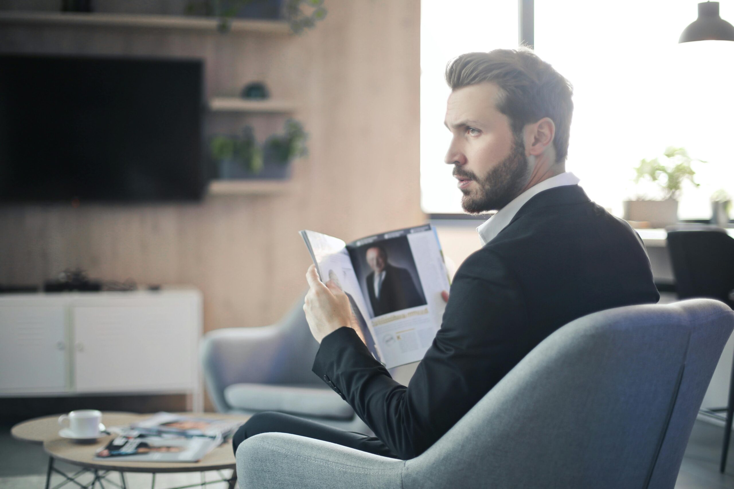 Image of business person reading a business magazine and looking off to the side.