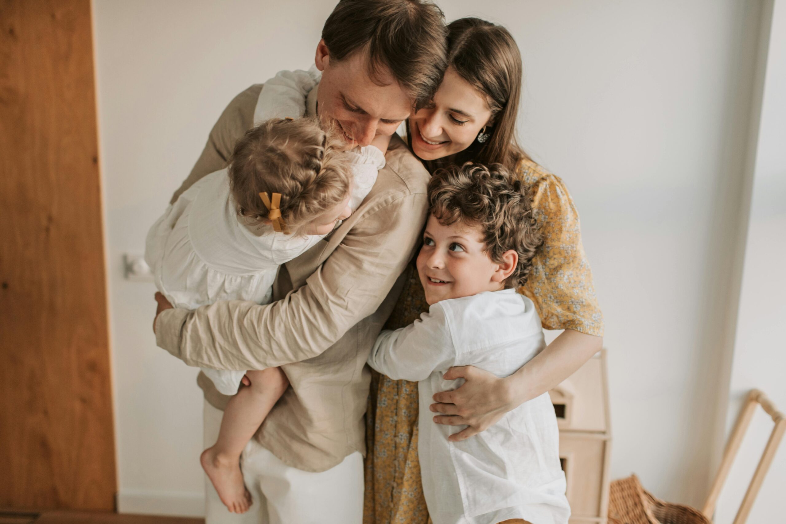 Image of mother and father hugging two young children.