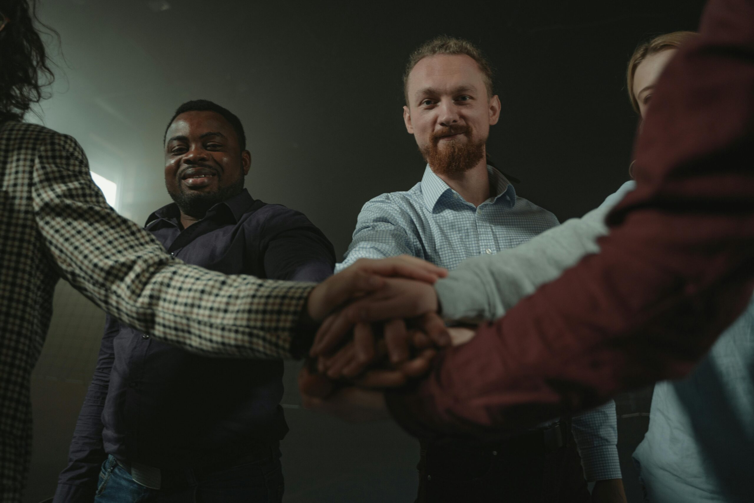 Image of people standing in a circle and joining hands with one another.