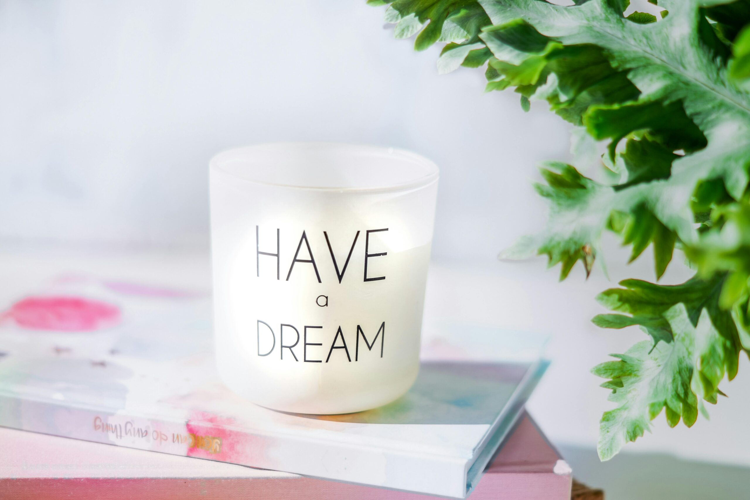 Image of candle on book and plant.