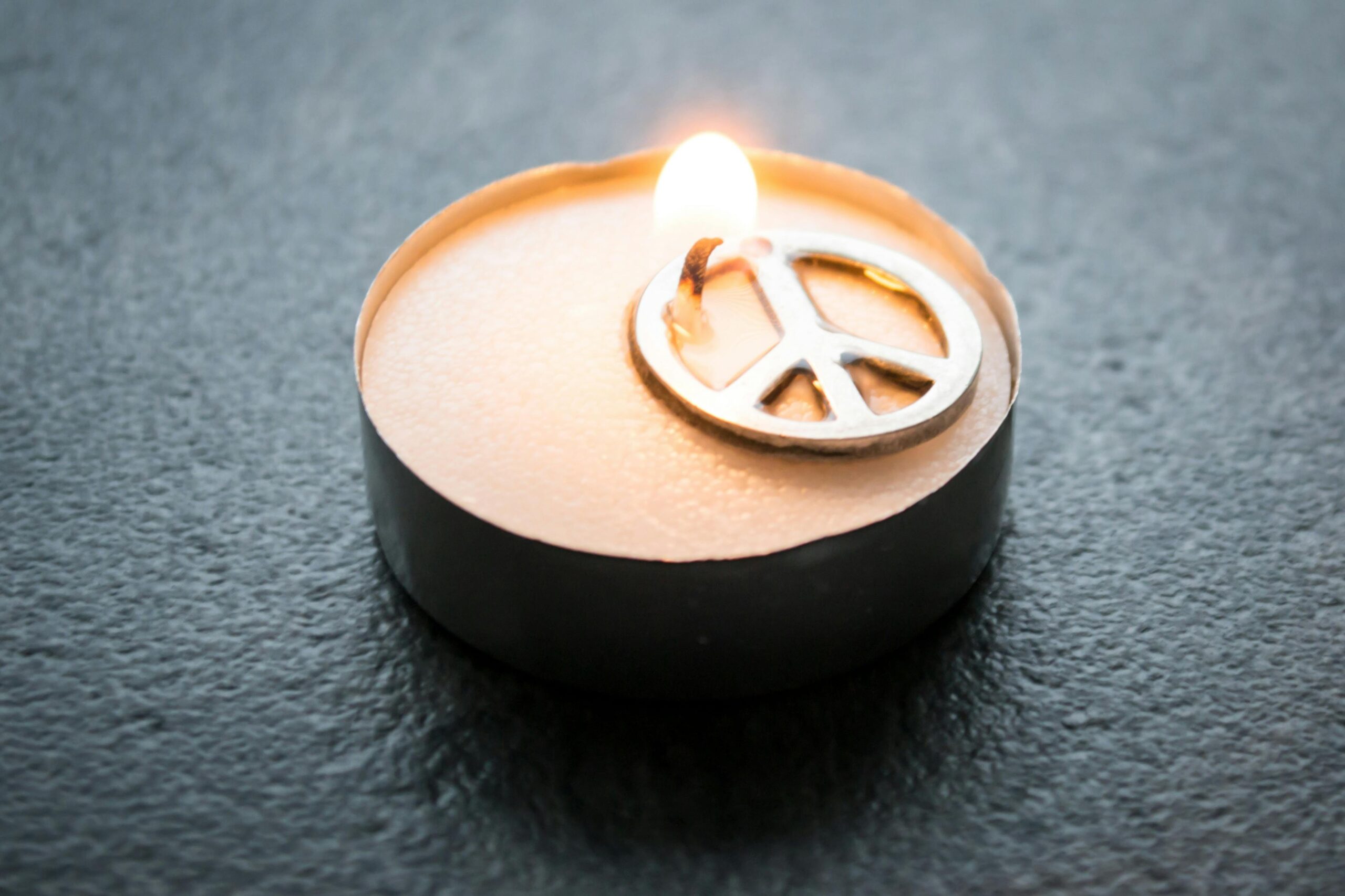 Image of lit candle with peace symbol within candle.