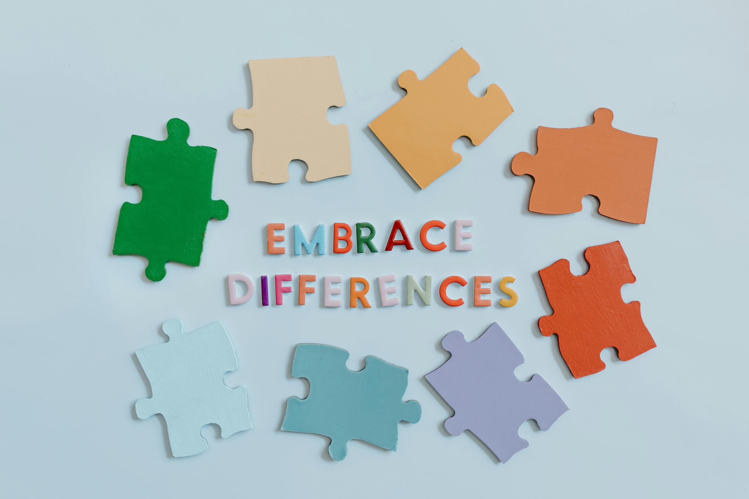 Image of puzzle pieces in various colors with the words "embrace differences" in the middle of the puzzle pieces.